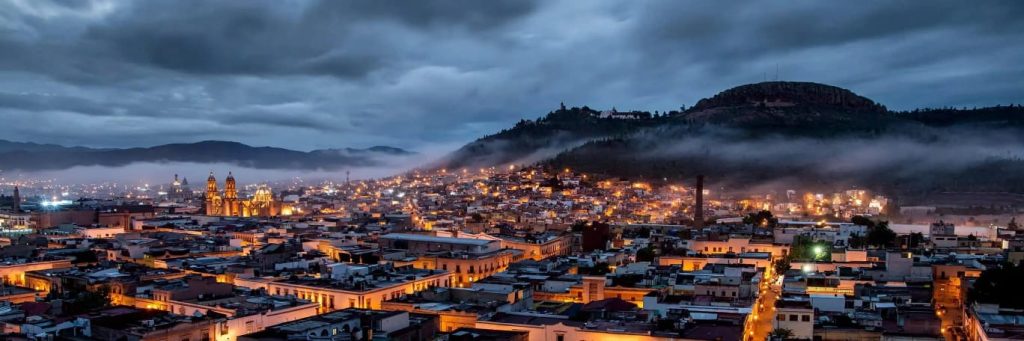 Vista nocturna de Zacatecas con cielo nublado y neblina sobre el Cerro de la Bufa
